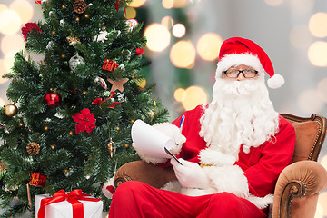 Image showing man in costume of santa claus with notepad