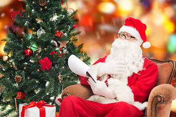 Image showing man in costume of santa claus with notepad