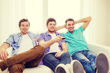Image showing smiling friends with remote control at home