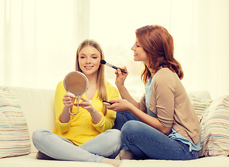Image showing two smiling teenage girls applying make up at home