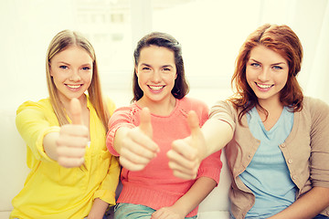 Image showing three girlfriends showing thumbs up at home