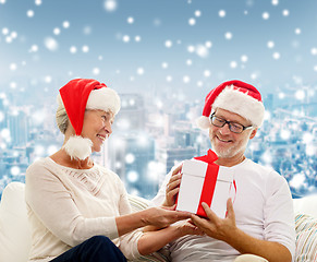 Image showing happy senior couple in santa hats with gift box