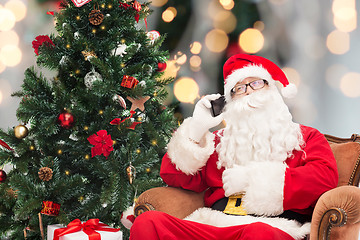 Image showing santa claus with smartphone and christmas tree