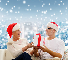 Image showing happy senior couple in santa hats with gift box