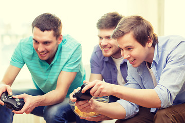 Image showing smiling friends playing video games at home