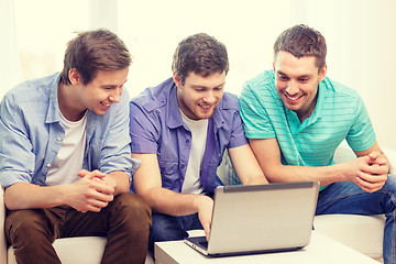 Image showing smiling friends with laptop computer at home