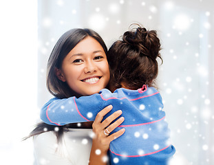 Image showing smiling little girl and mother hugging indoors