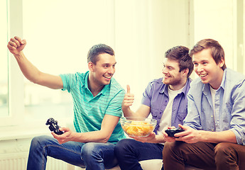 Image showing smiling friends playing video games at home