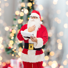 Image showing man in costume of santa claus with notepad