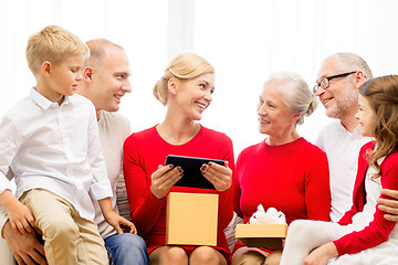 Image showing smiling family with tablet pc and gift box at home