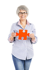 Image showing Elderly woman holding a puzzle piece