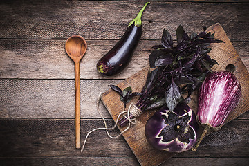 Image showing Aubergines, basil and spoon on wooden table