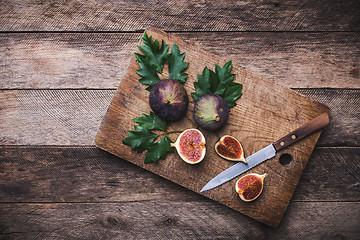 Image showing rustic style Cut figs with knife on chopping board and wooden ta
