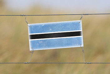 Image showing Border fence - Old plastic sign with a flag