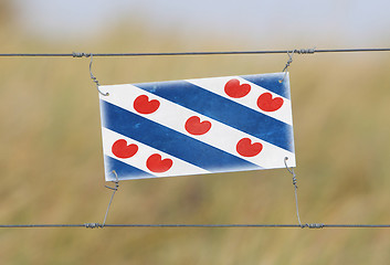 Image showing Border fence - Old plastic sign with a flag