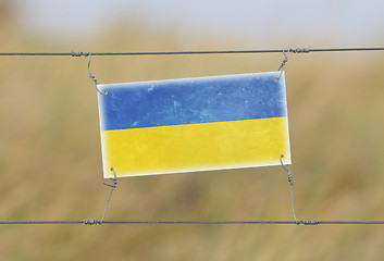 Image showing Border fence - Old plastic sign with a flag