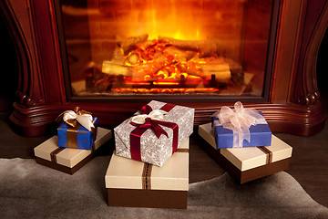 Image showing Christmas gift boxes near fireplace