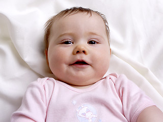 Image showing Baby girl lying on a blanket looking into the camera