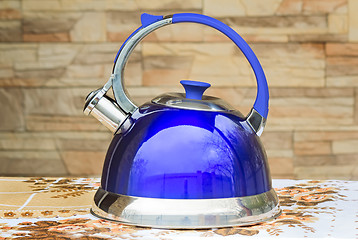 Image showing Bright blue kettle on the tablecloth table.