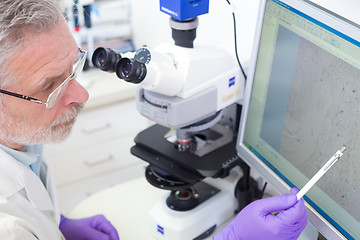 Image showing Senior scientist  microscoping in lab.