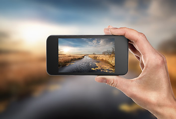 Image showing Phone in hand and landscape