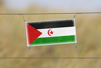 Image showing Border fence - Old plastic sign with a flag