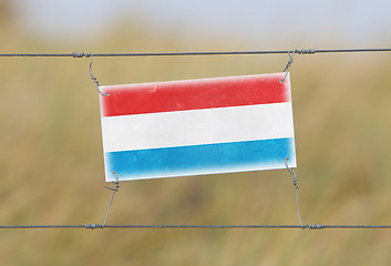 Image showing Border fence - Old plastic sign with a flag