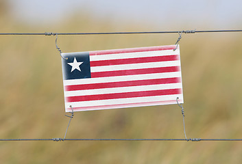 Image showing Border fence - Old plastic sign with a flag