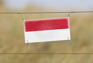 Image showing Border fence - Old plastic sign with a flag