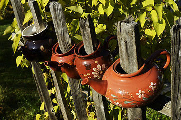 Image showing four ceramic teapot on a fence