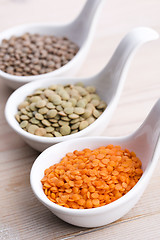 Image showing Three kinds of lentil in bowls - red lentil, green lentil and br