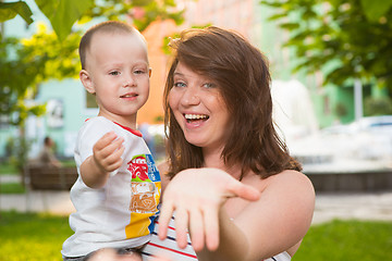 Image showing Laughing young pregnant mother playing with her son in a beautiful garden