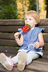 Image showing Beautiful little girl holding strawberry shaped lollipop