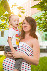 Image showing Laughing young pregnant mother playing with her son in a beautiful garden