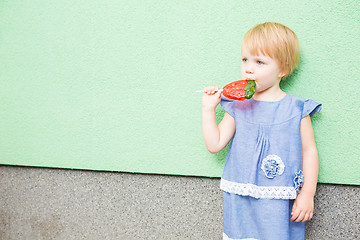 Image showing Beautiful little girl holding strawberry shaped lollipop