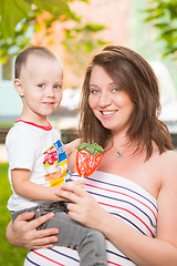 Image showing Laughing young pregnant mother playing with her son in a beautiful garden