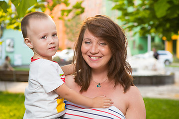 Image showing Laughing young pregnant mother playing with her son in a beautiful garden