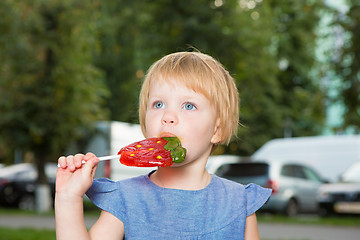 Image showing Beautiful little girl holding strawberry shaped lollipop