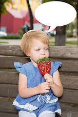 Image showing Beautiful little girl holding strawberry shaped lollipop