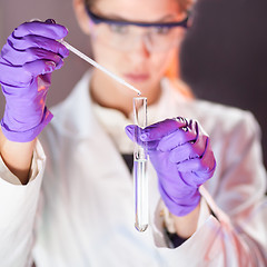 Image showing Attractive young scientist pipetting.