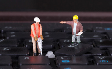 Image showing Miniature workers with drill working on keyboard