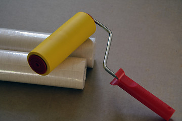 Image showing Two rolls of wallpaper in wrap and a roller
