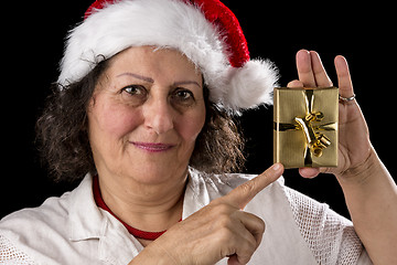 Image showing Mature Woman with Red Cap Pointing at Golden Gift