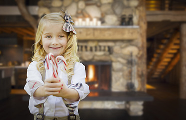 Image showing Cute Young Girl Holding Candy Canes in Rustic Cabin