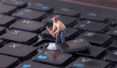 Image showing Miniature worker with pickaxe working on keyboard