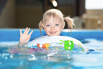 Image showing Little blond girl swimming in water pool