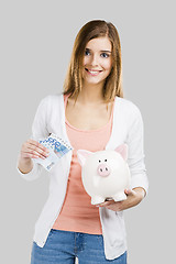 Image showing Beautiful woman putting money in a piggy bank