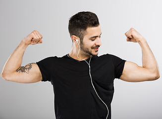 Image showing Man listen  music and looking his muscles