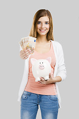 Image showing Beautiful woman putting money in a piggy bank
