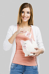 Image showing Beautiful woman putting money in a piggy bank